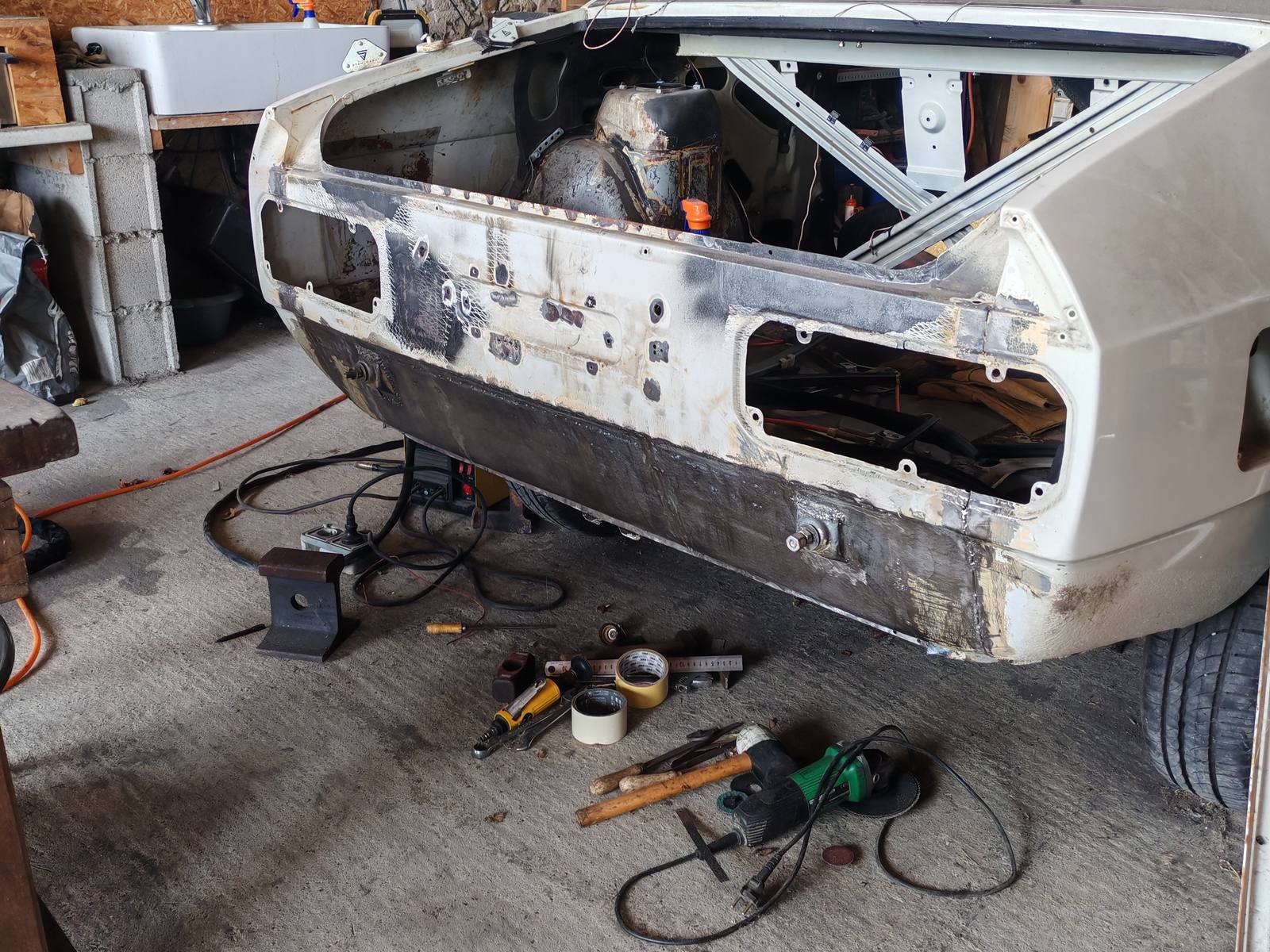 Carrosserie ancienne en cours de décapage laser : le bas de caisse est revenu au métal nu