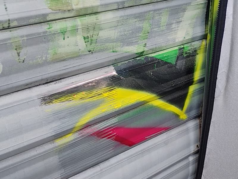 Effacement d'un graffiti sur un rideau métallique au laser pulsé, en conditions réelles de chantier